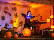 Valaistu lava, jossa halloween-koristeita ja esiintyjä.